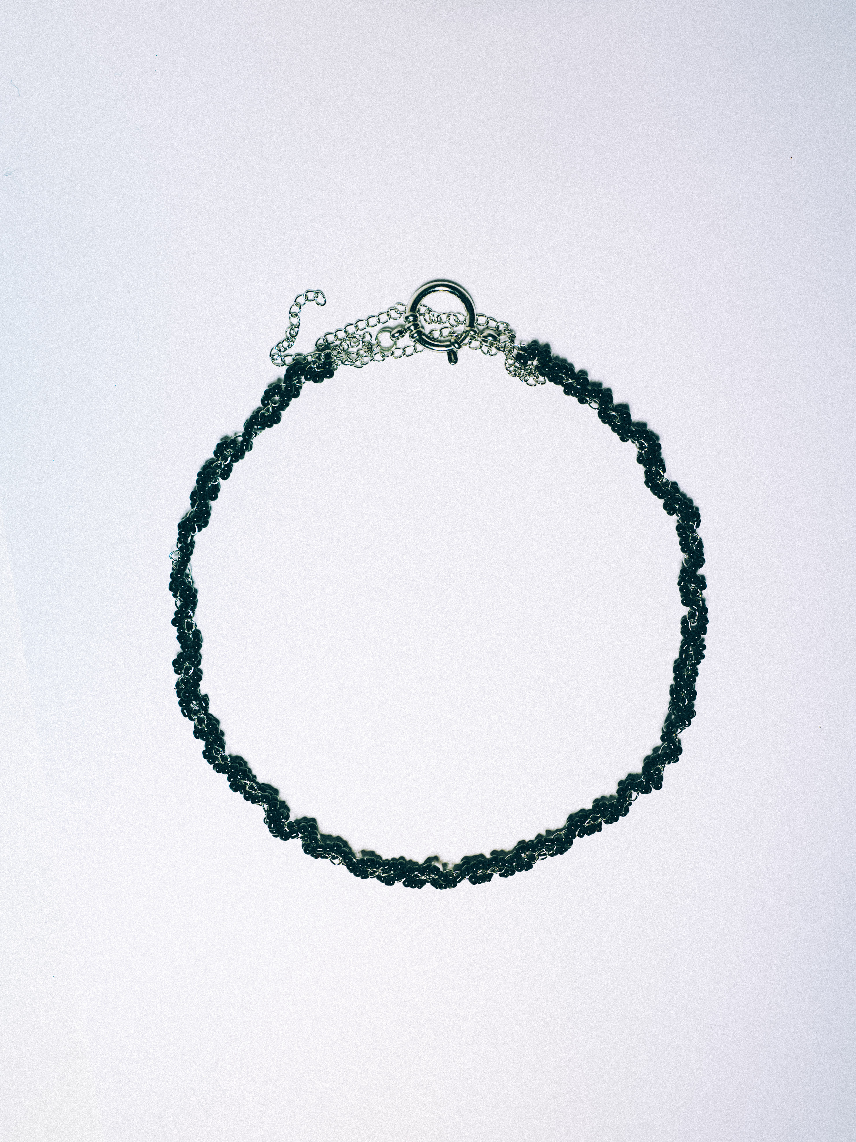 Black beaded necklace woven with a silver-tone chain
