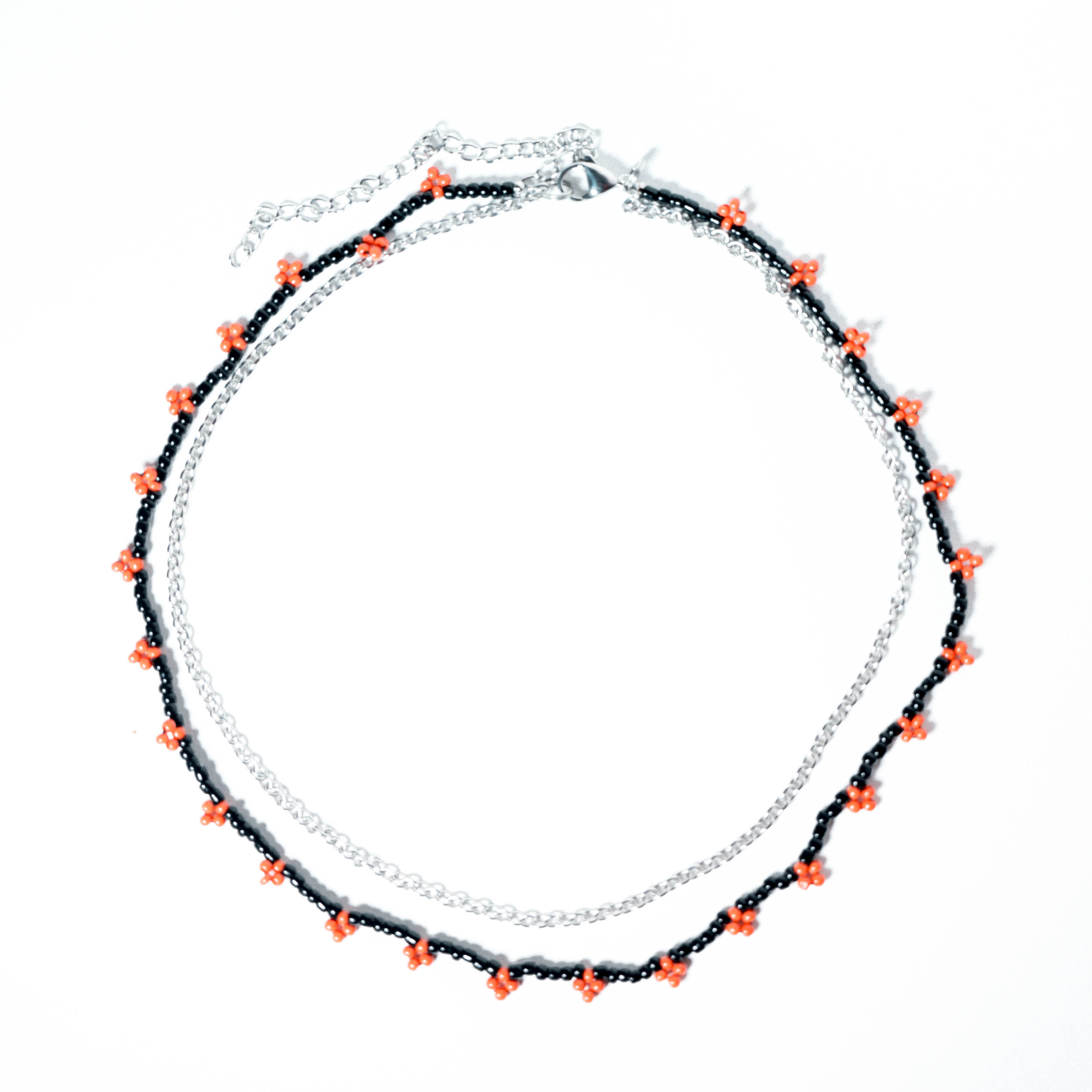 Black beaded necklace with small red flower details and silver chain